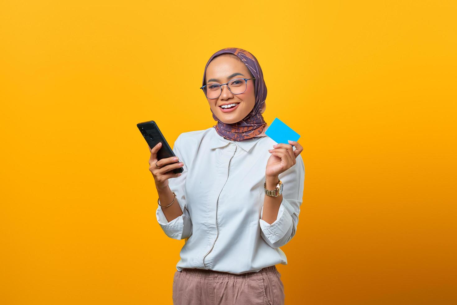 Cheerful Asian woman holding smartphone and showing blank card photo