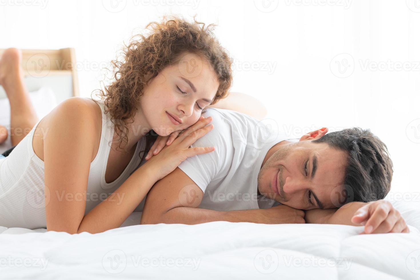 parejas felices descansando en el dormitorio blanco del apartamento foto