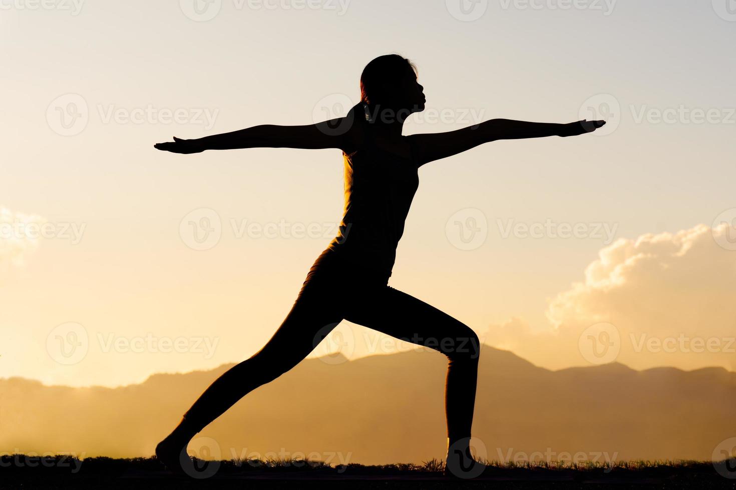 Silhouette woman practicing yoga on top of mountain photo