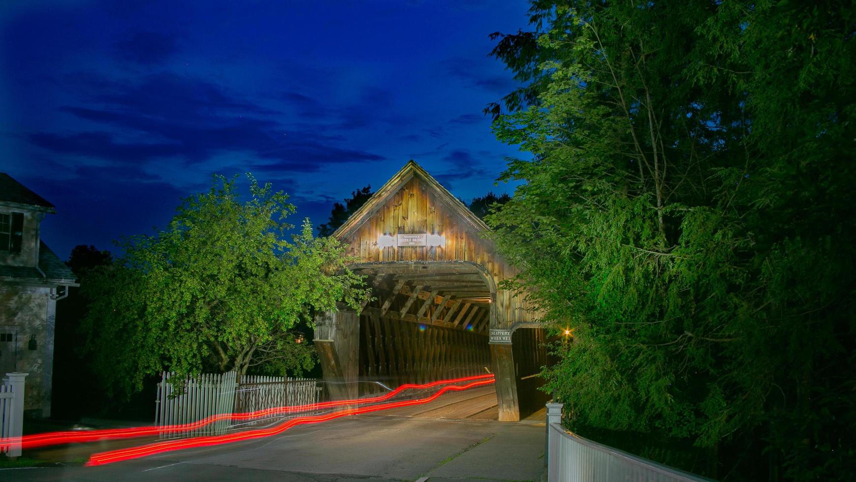 Red tail lights of a car passing throuh a covered bridge photo
