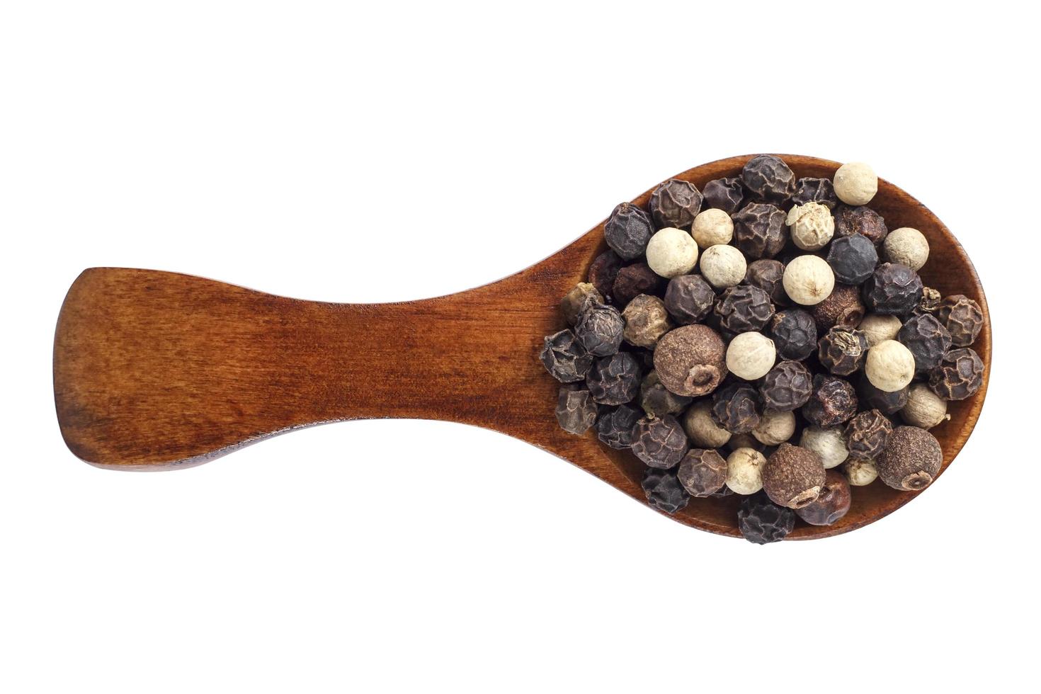 Conjunto de pimienta en cuchara de madera aislado foto