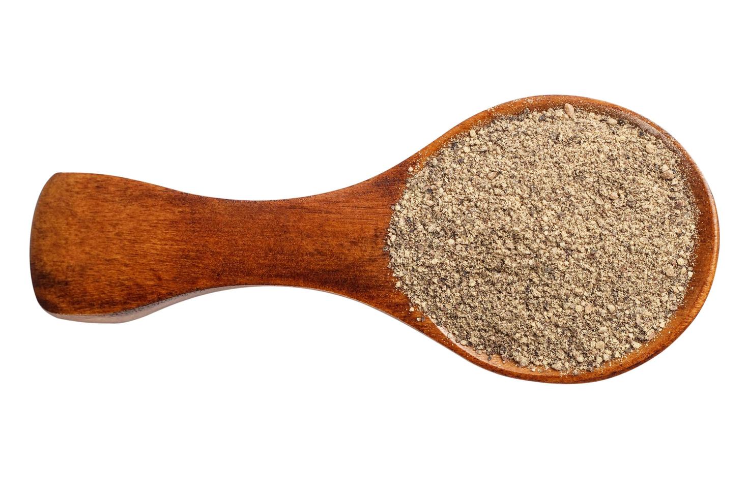 Ground black pepper in a wooden spoon photo