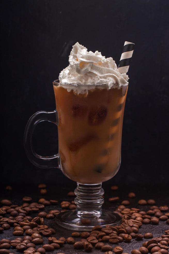 café frío con hielo y leche en un vaso y crema batida encima foto