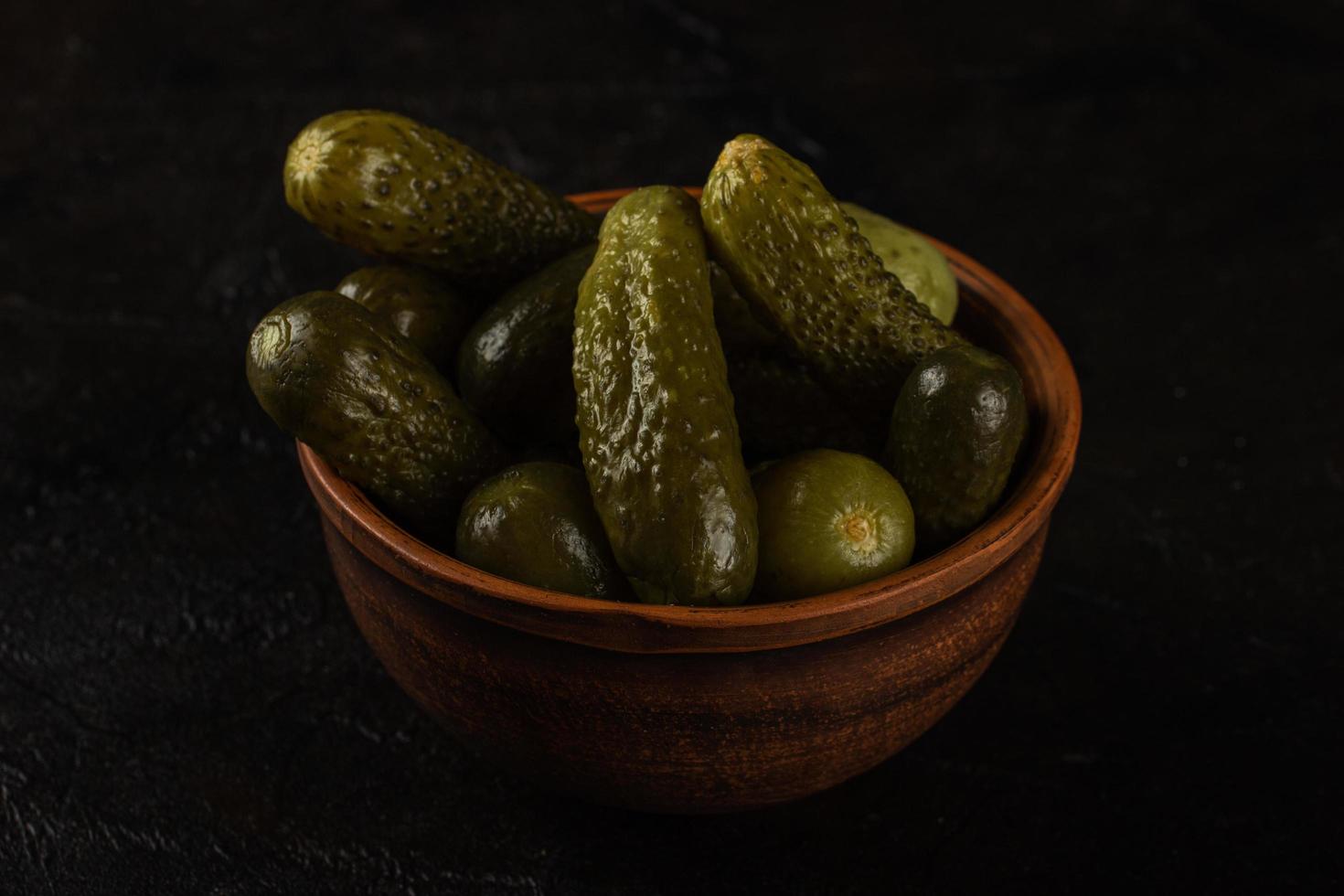 Cucumbers in a clay bowl on a dark concrete background photo