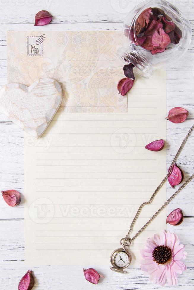 pétalos de flores sobre de carta botella de vidrio reloj de bolsillo corazón artesanal foto