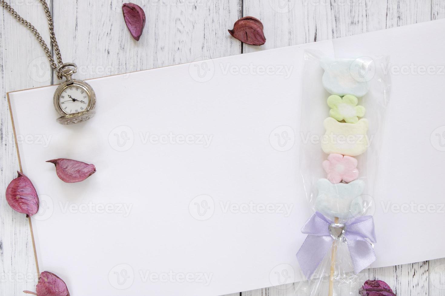 mesa de madera pintada de blanco papel pétalos de flores reloj de bolsillo de algodón de azúcar foto