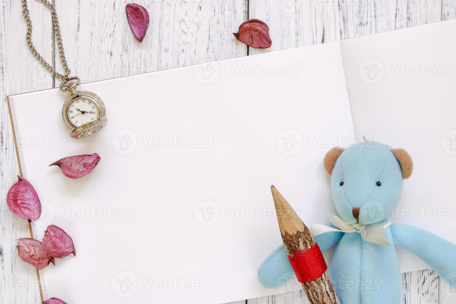 Paper with a toy, pencil, watch and petals photo