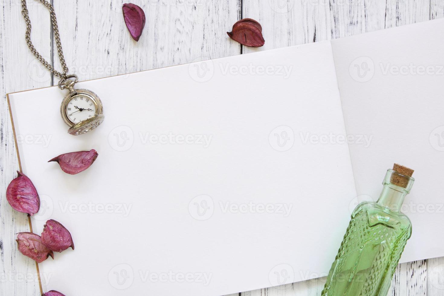 Watch, bottle and petals with paper photo