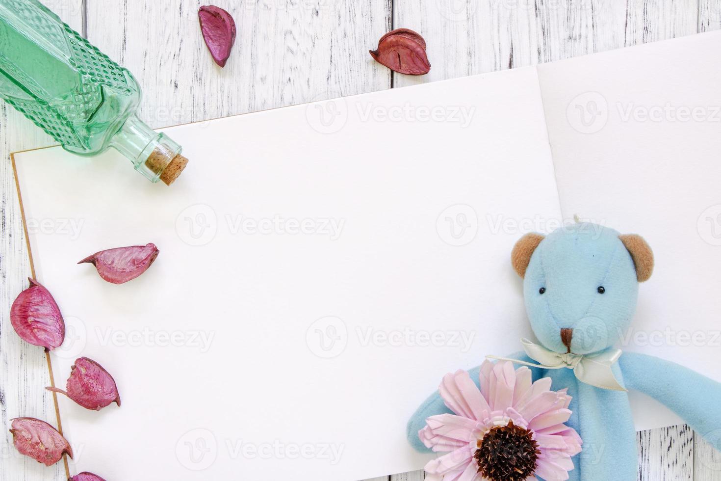 Paper with toy, flower, petals, and bottle photo