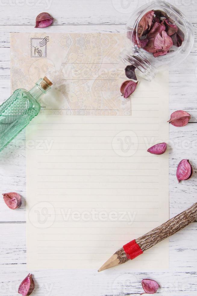 Paper with petals, pencil and bottle photo