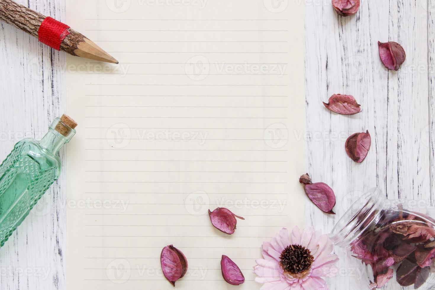 Paper with petals, pencil and bottle photo