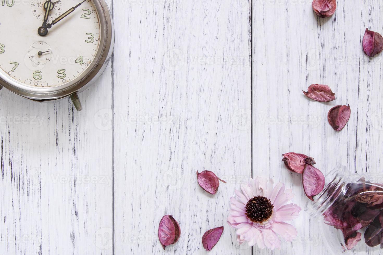 Petals and clock on white wood photo
