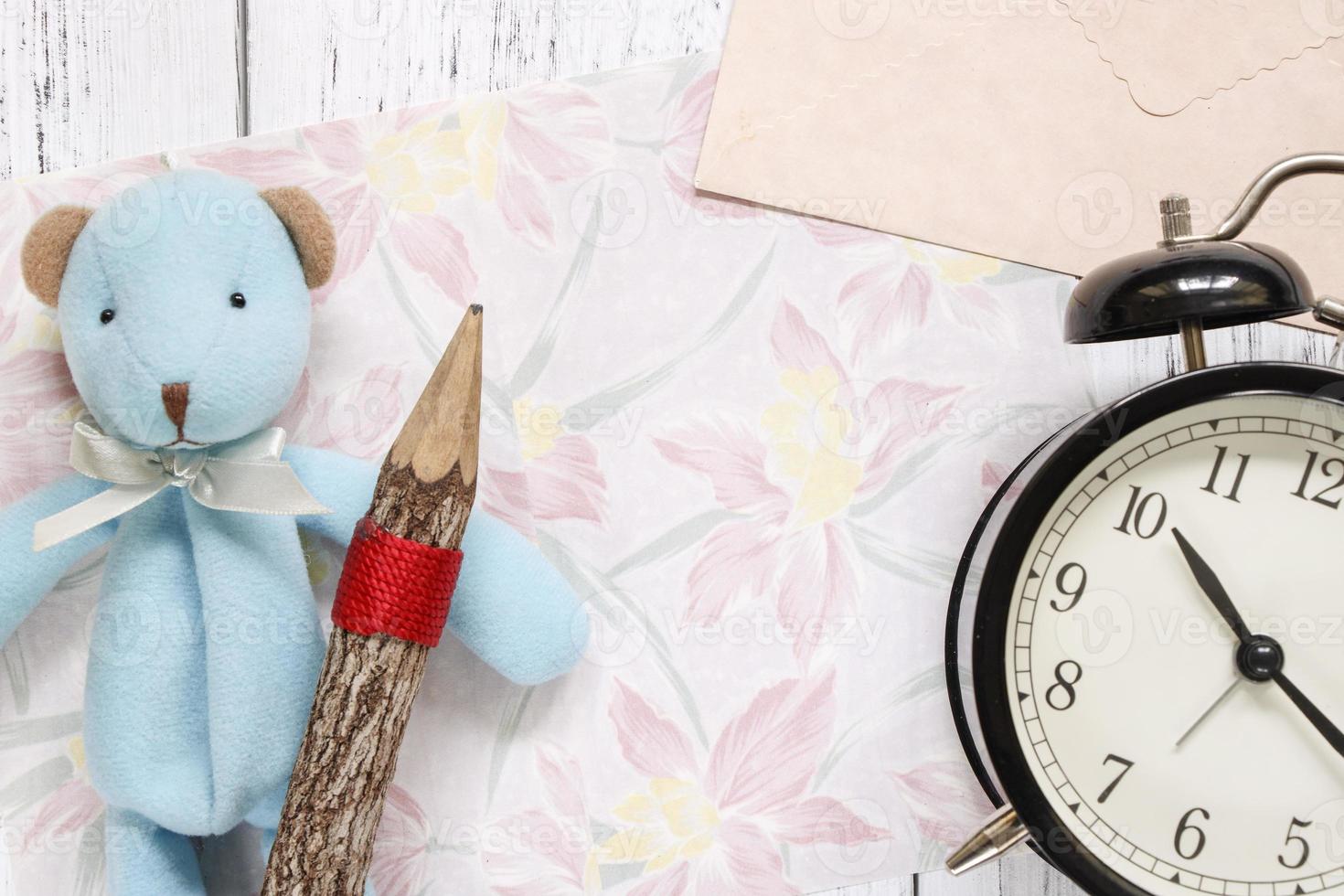 papel floral con un juguete, lápiz y reloj foto