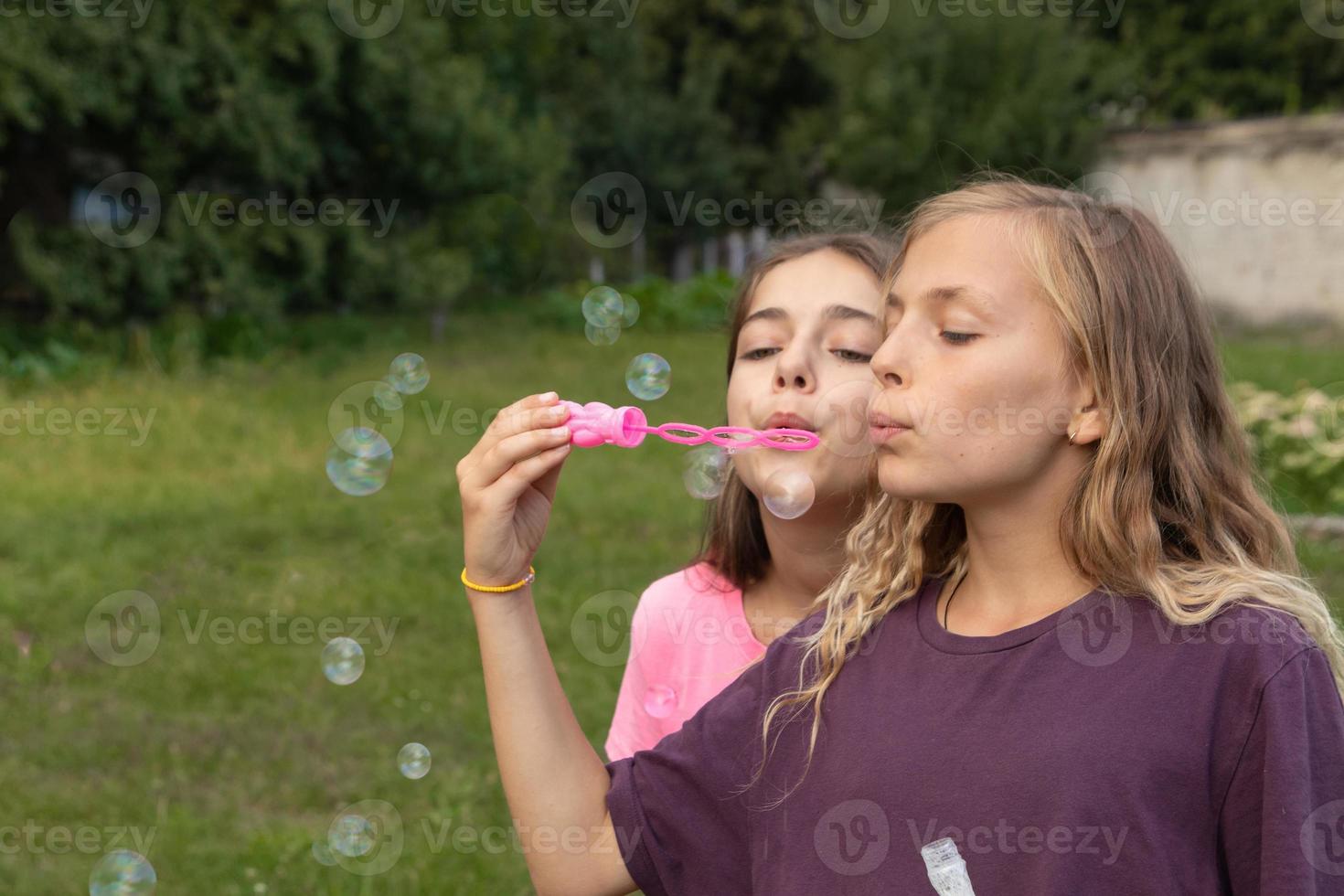 Two girls blowing soap bubbles - carefree and fun time and friendship photo