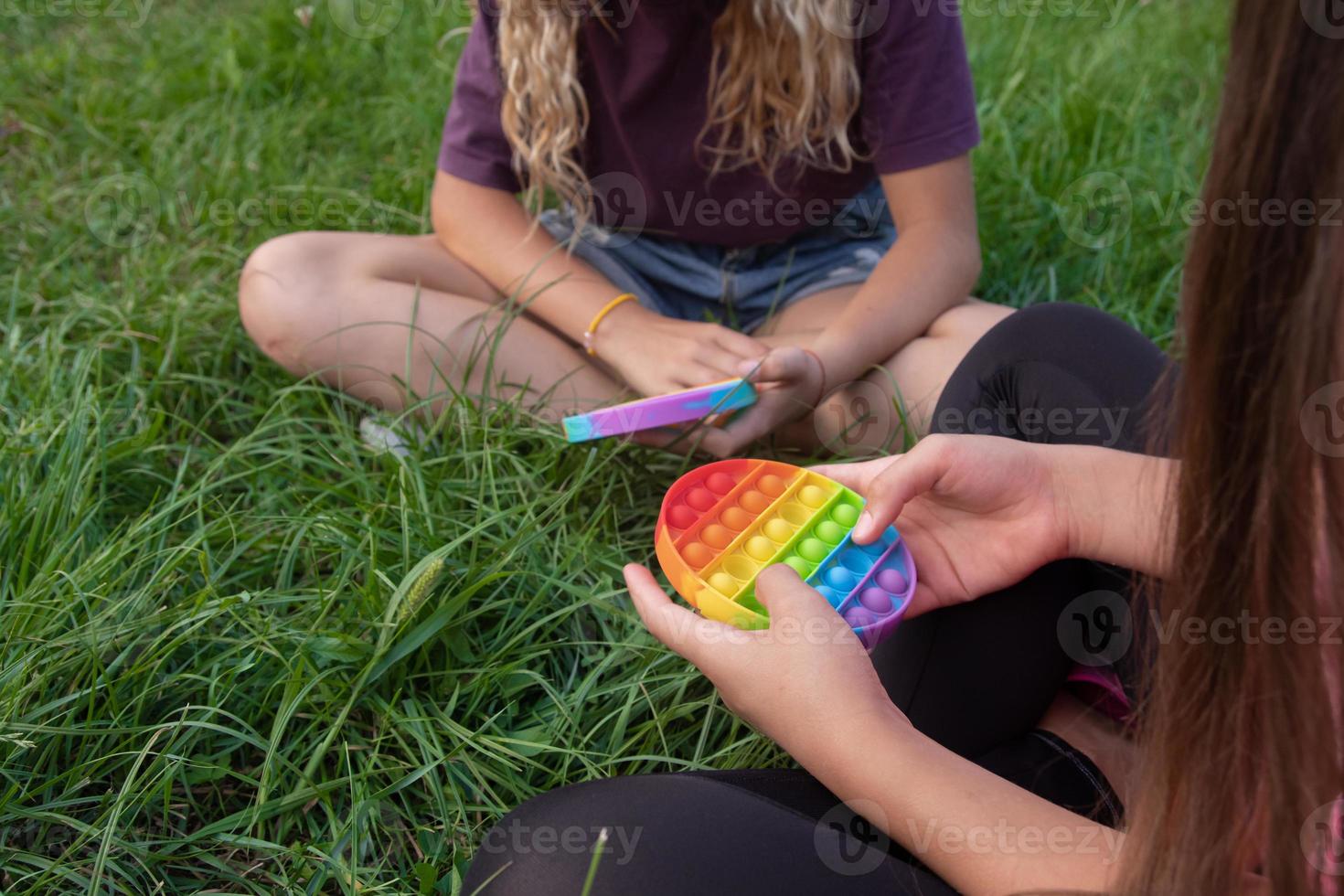 las niñas juegan al juguete popular pop-it con toque de silicona colorido foto