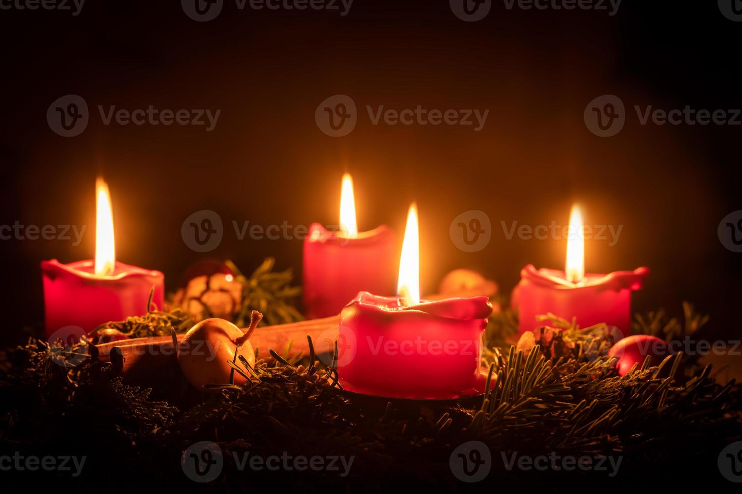 Decorated advent wreath made of fir branches with burning red candles photo