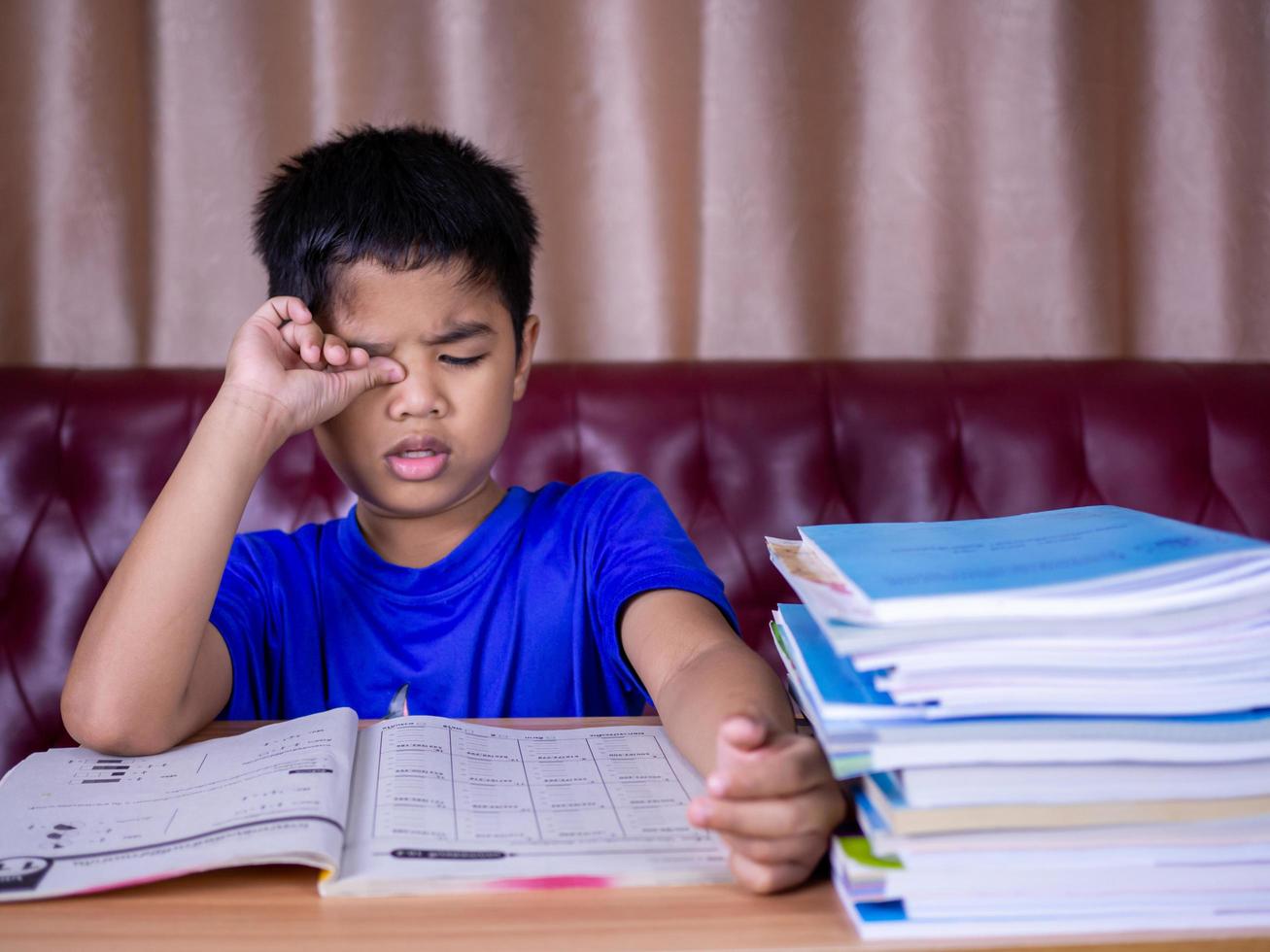 un niño está cansado de leer un libro en una mesa de madera. foto