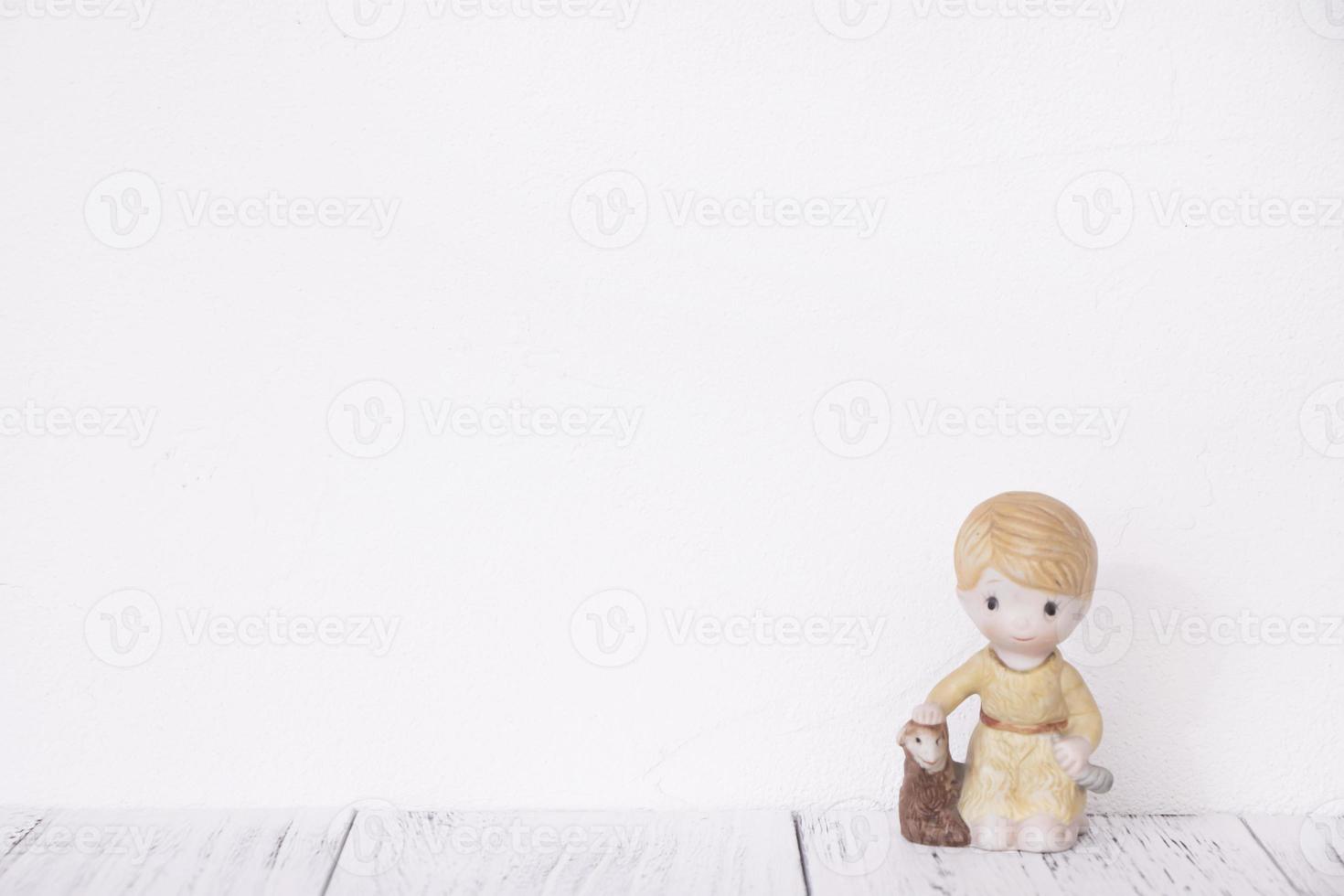 Ceramic doll on white wall photo