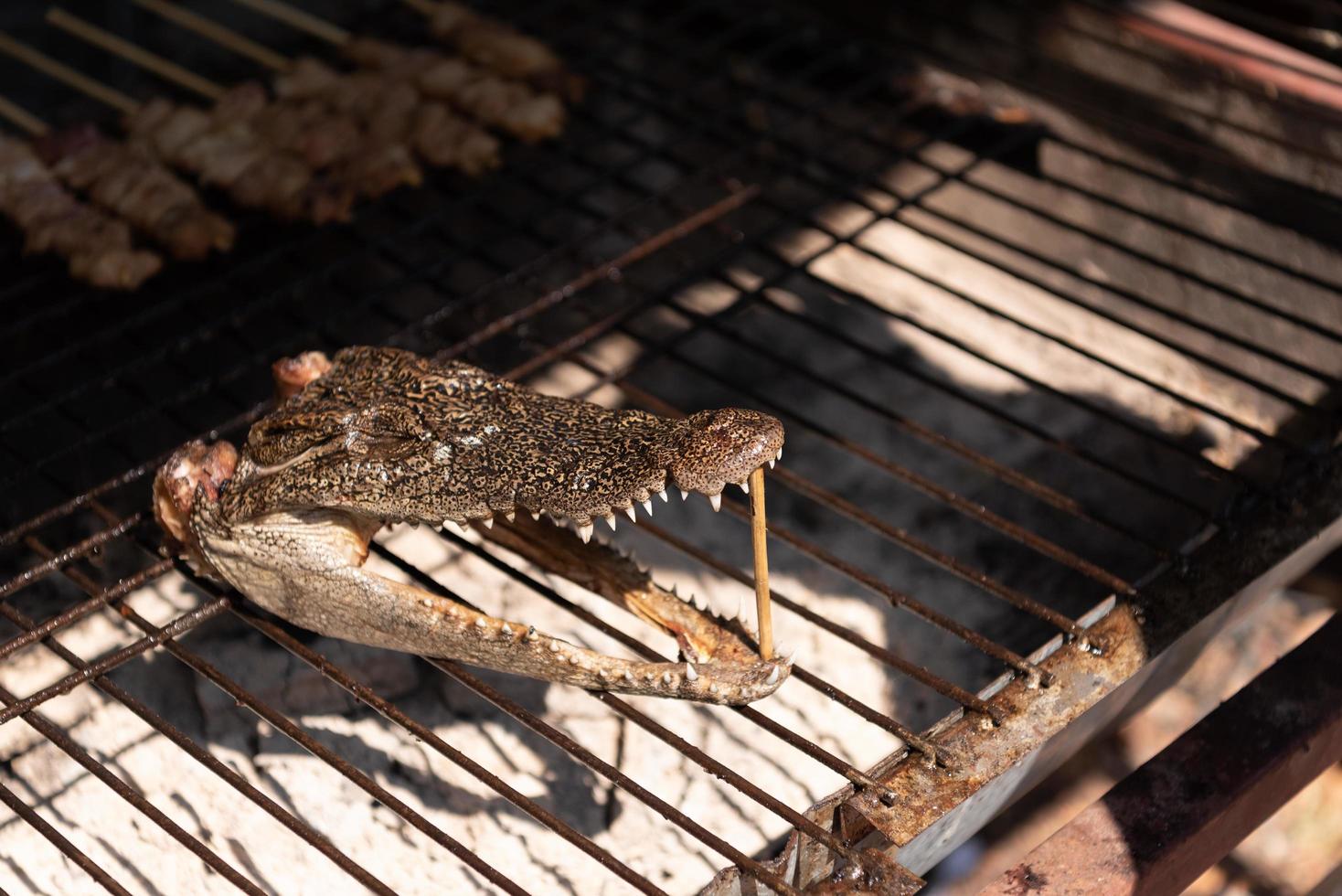 Cerca de la cabeza de cocodrilo asado en estufa de carbón foto