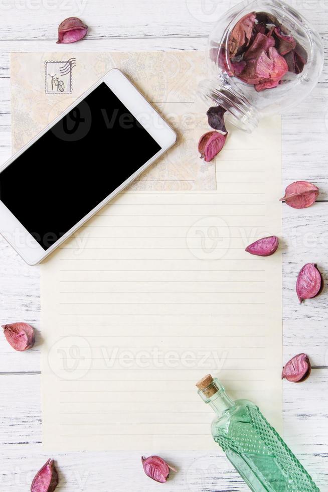 Paper with phone, petals, and bottle photo