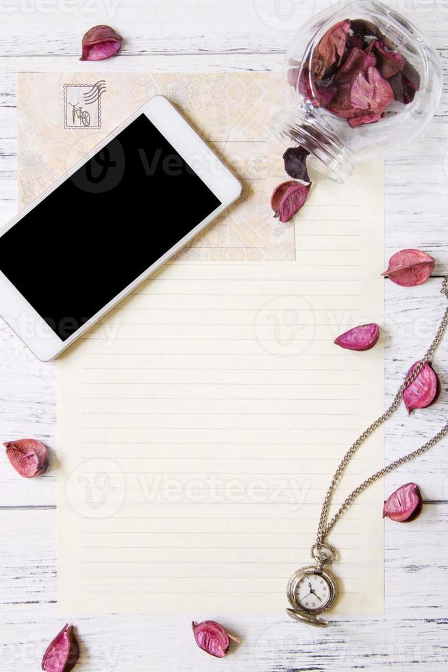 Paper with phone, watch, and petals photo