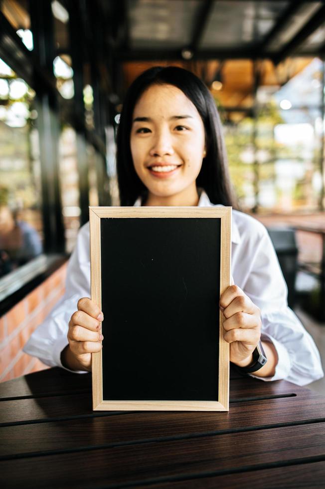 smile woman holding black board in cafe photo