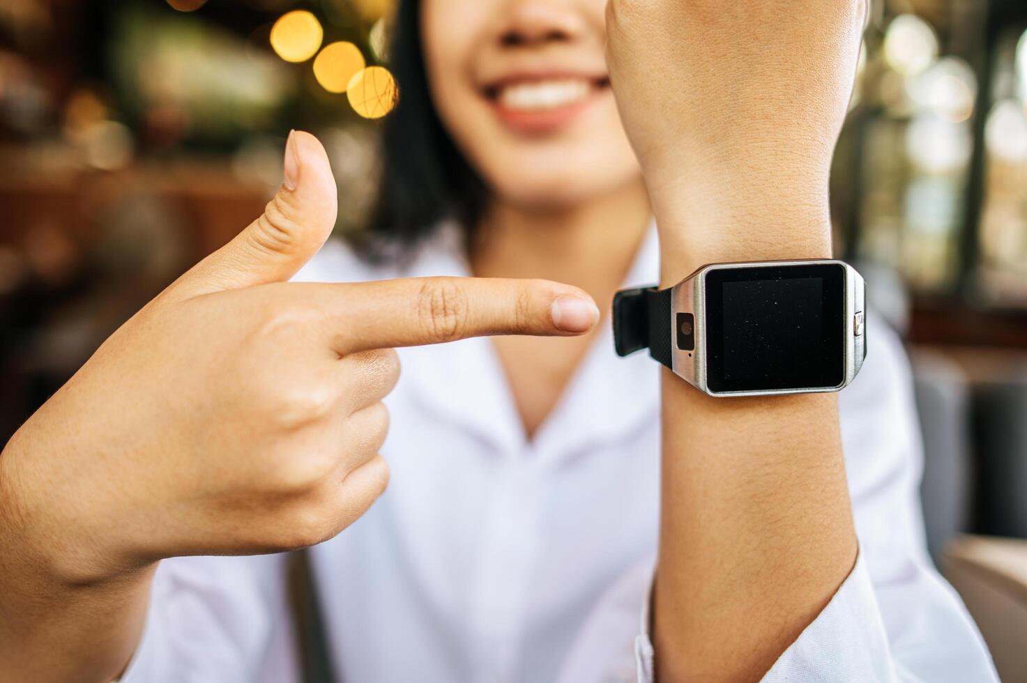 A smart watch on the wrist with a right hand pointing at it. photo