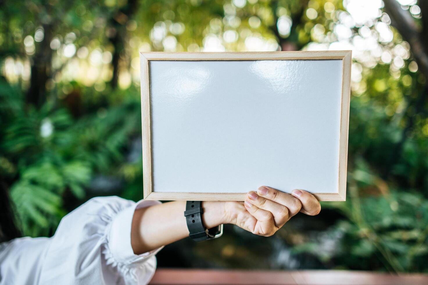 hand woman holding white board in the garden photo