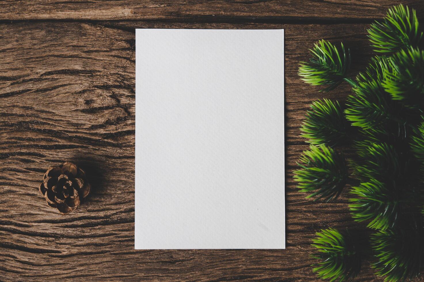 A blank card is placed on envelope and leaf with wood background photo