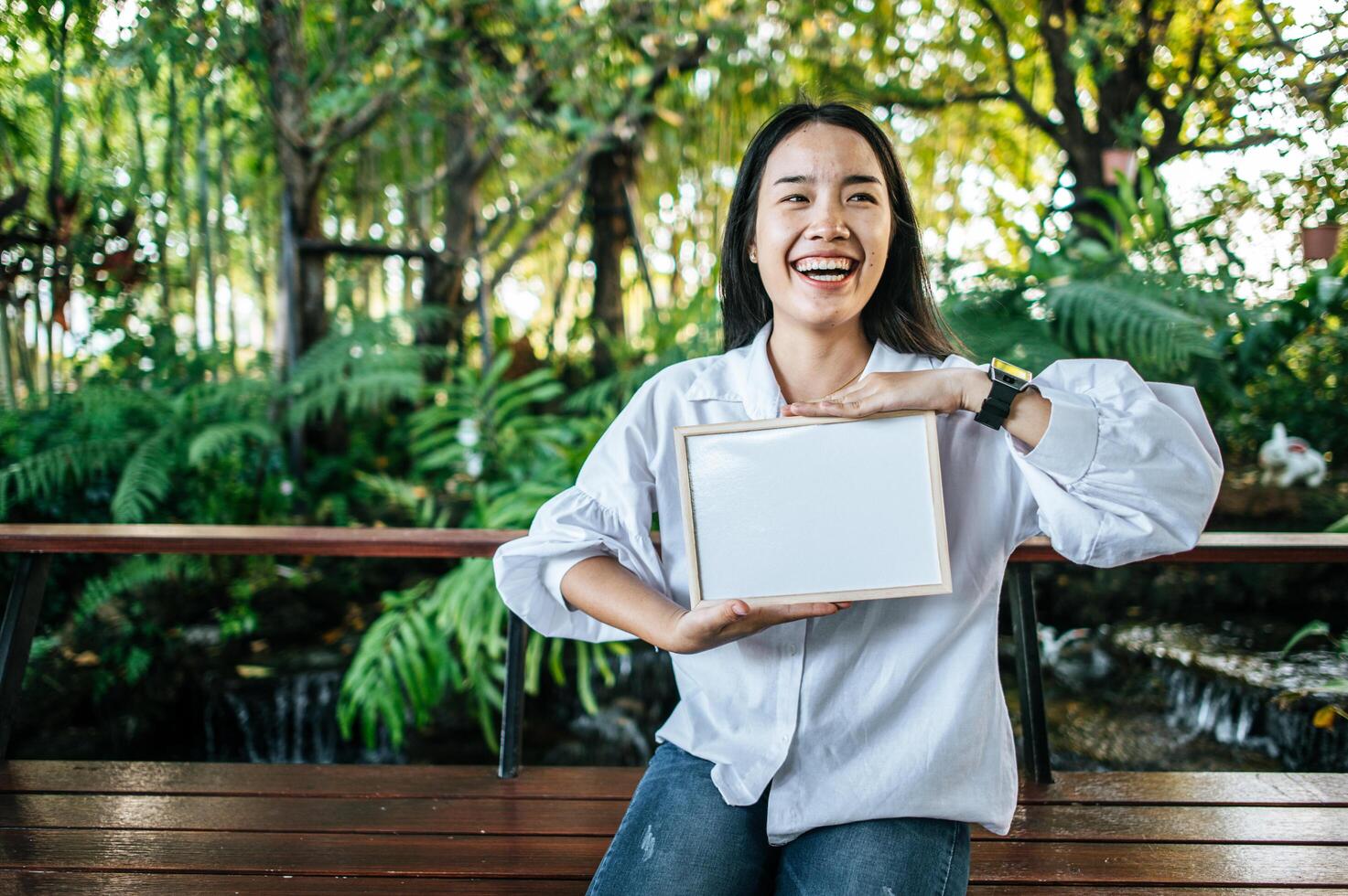 Sonrisa mujer sosteniendo pizarra en el jardín foto