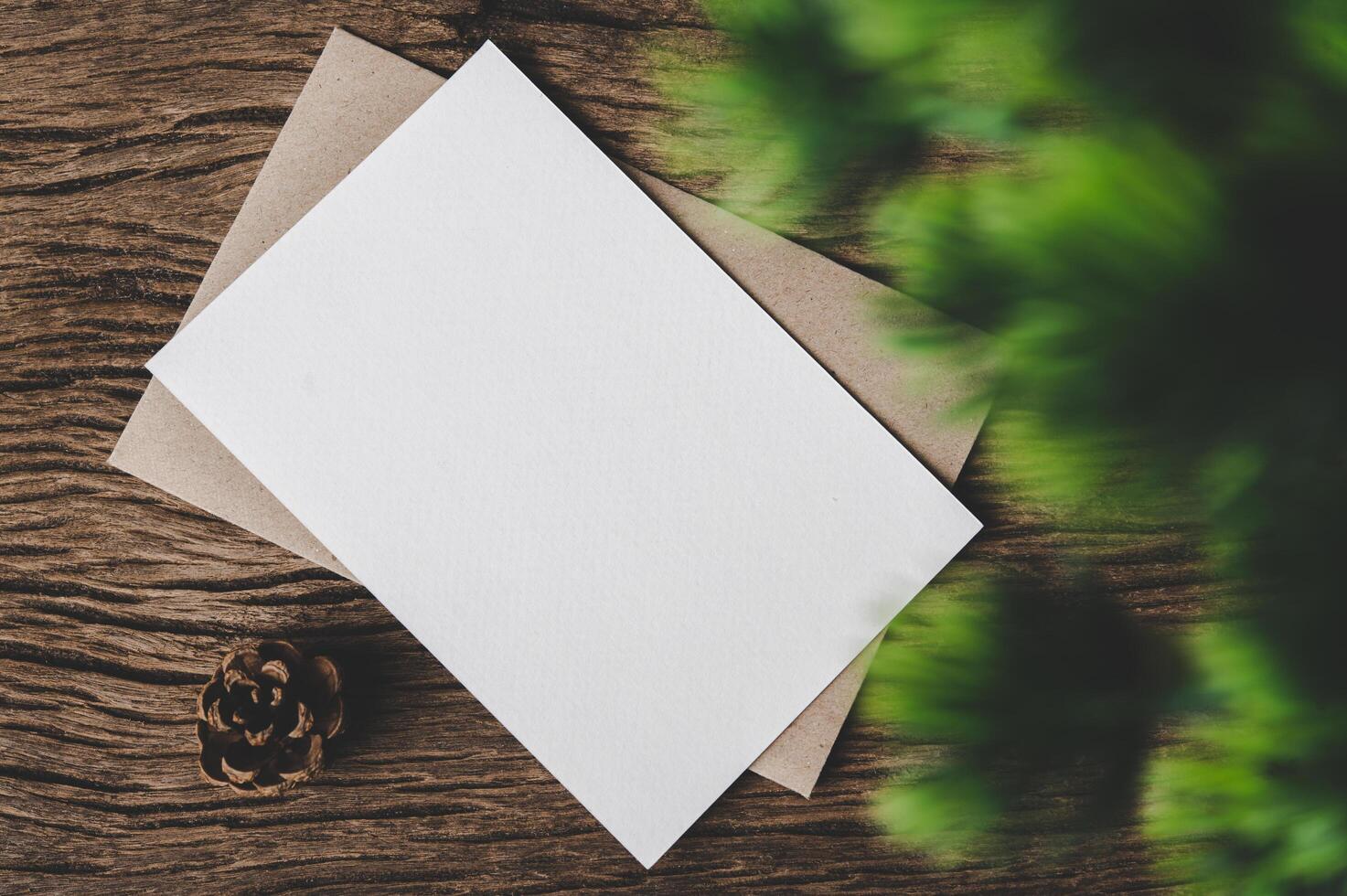 A blank card is placed on envelope and leaf with wood background photo