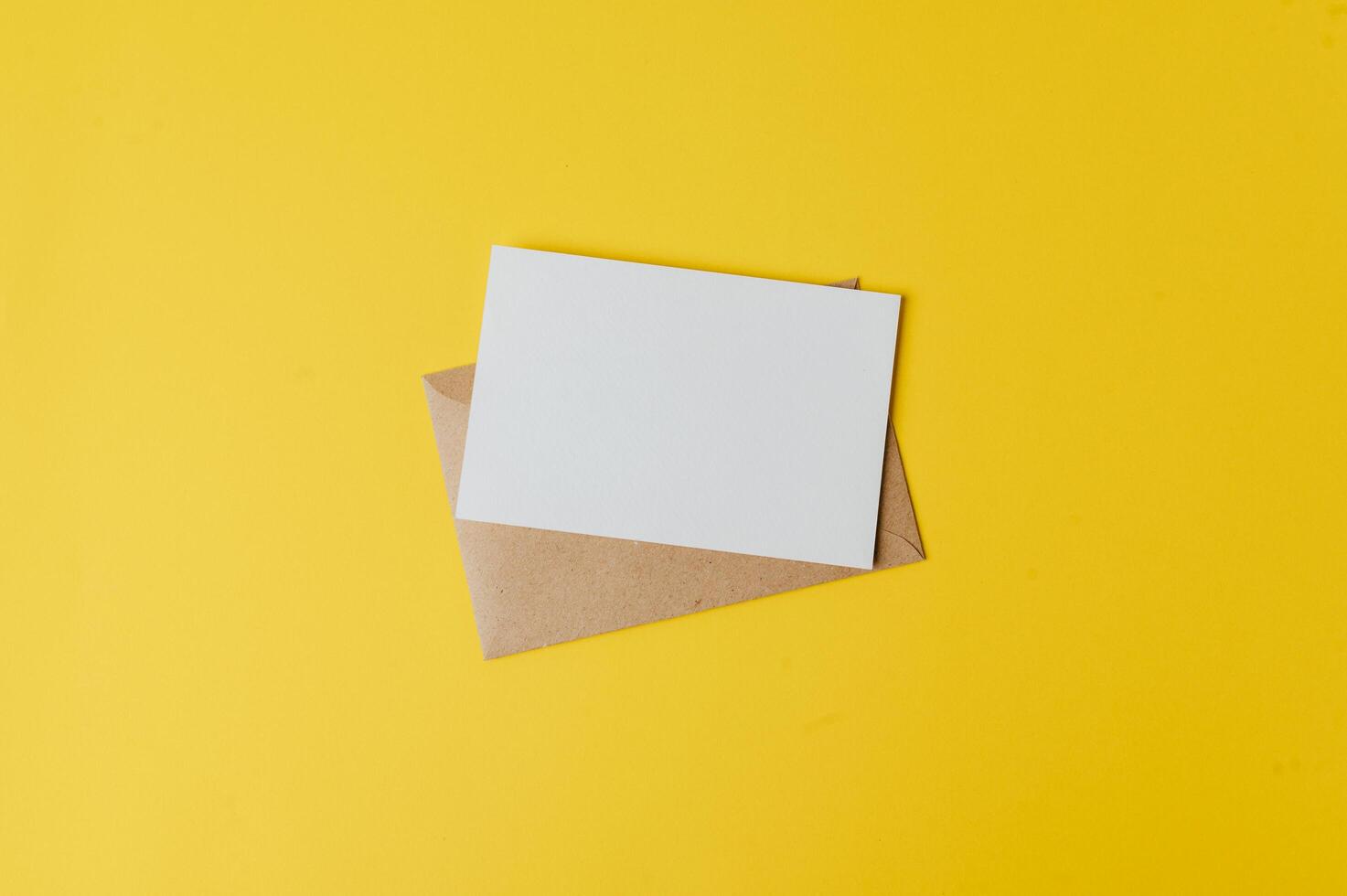 A blank card with envelope is placed on yellow background photo