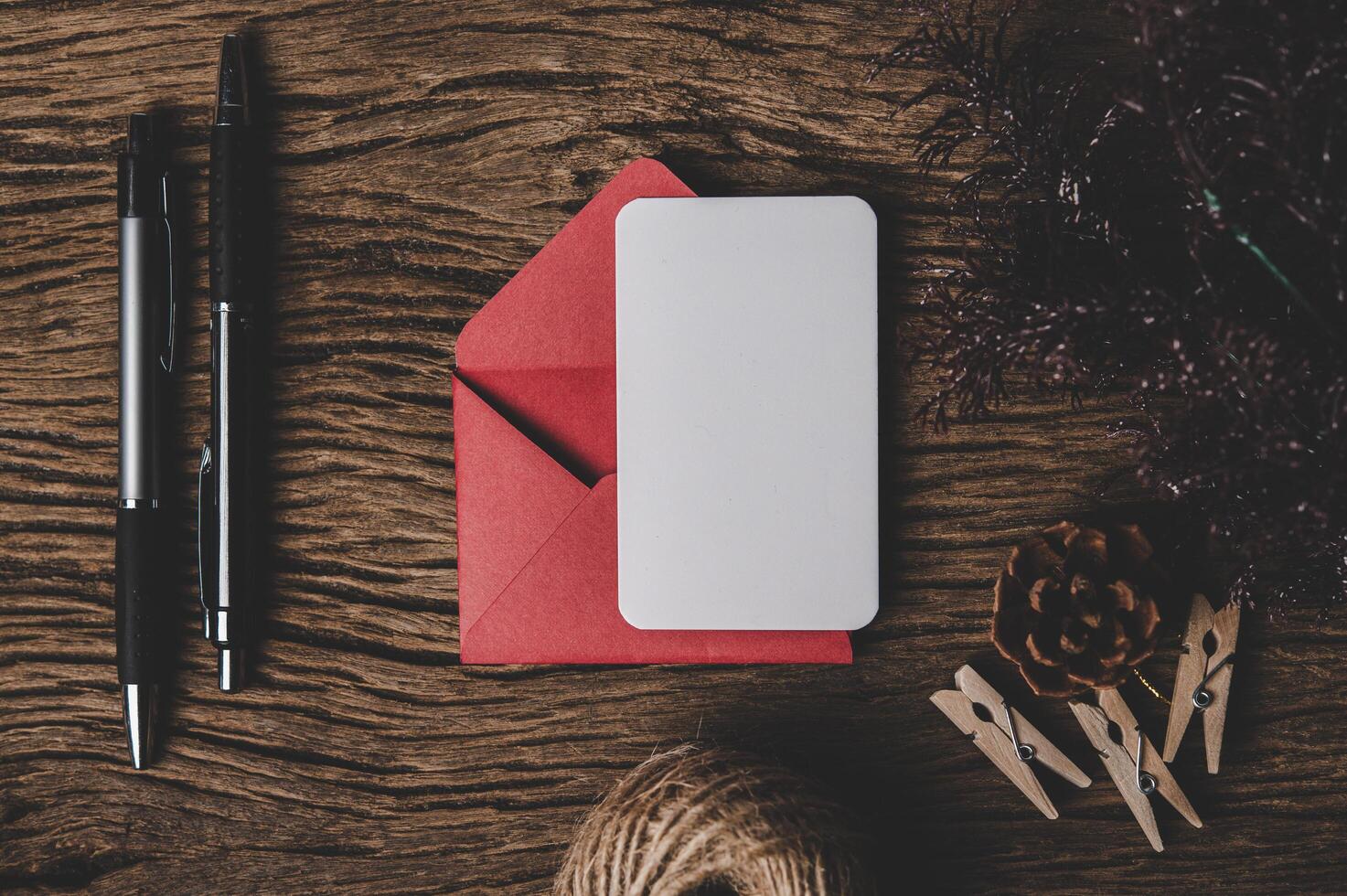 A blank card with red envelope and two pen is placed on wood. photo