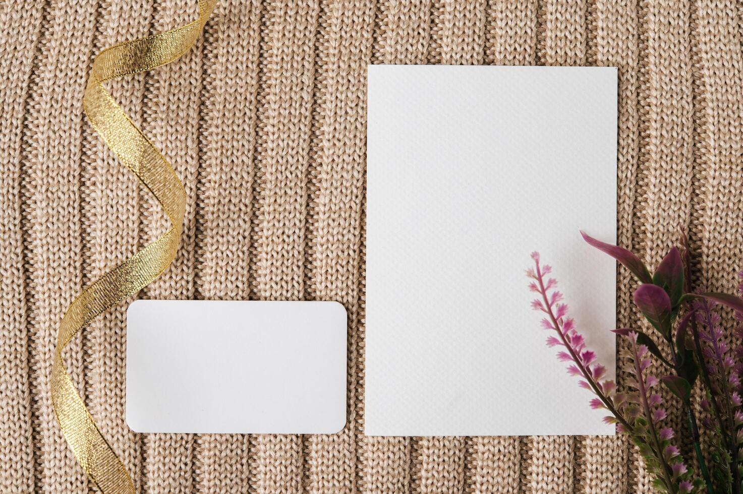 dos tarjetas en blanco, ribbin dorado y una hoja en un suéter foto