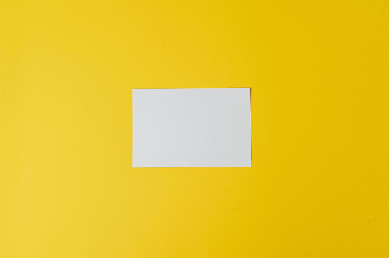 A blank card is placed on yellow background photo