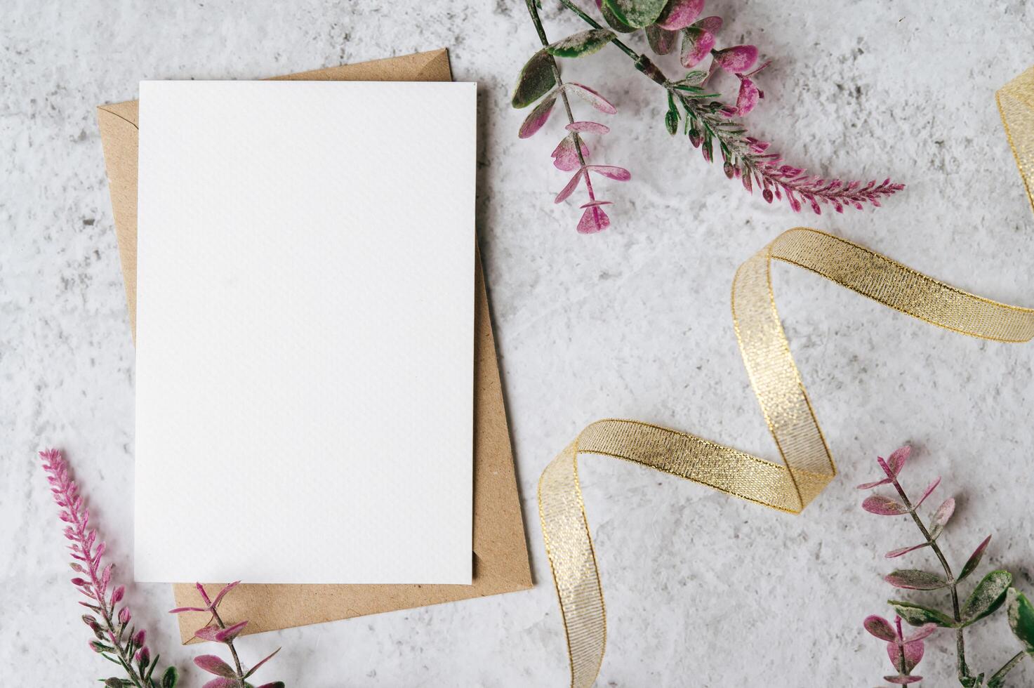 Se coloca una tarjeta en blanco con sobre y flor sobre fondo blanco. foto