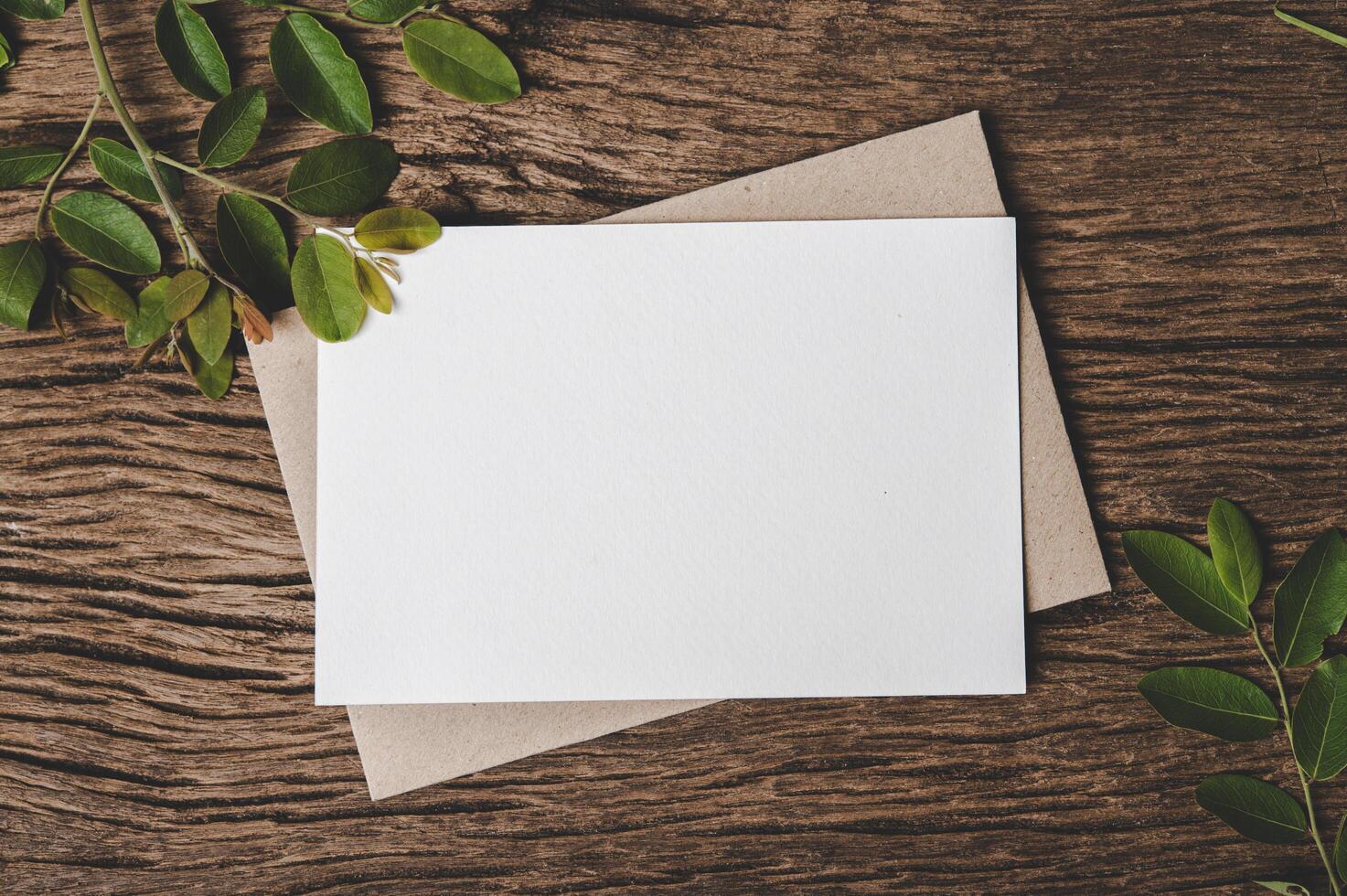 A blank card is placed on envelope and leaf with wood background photo