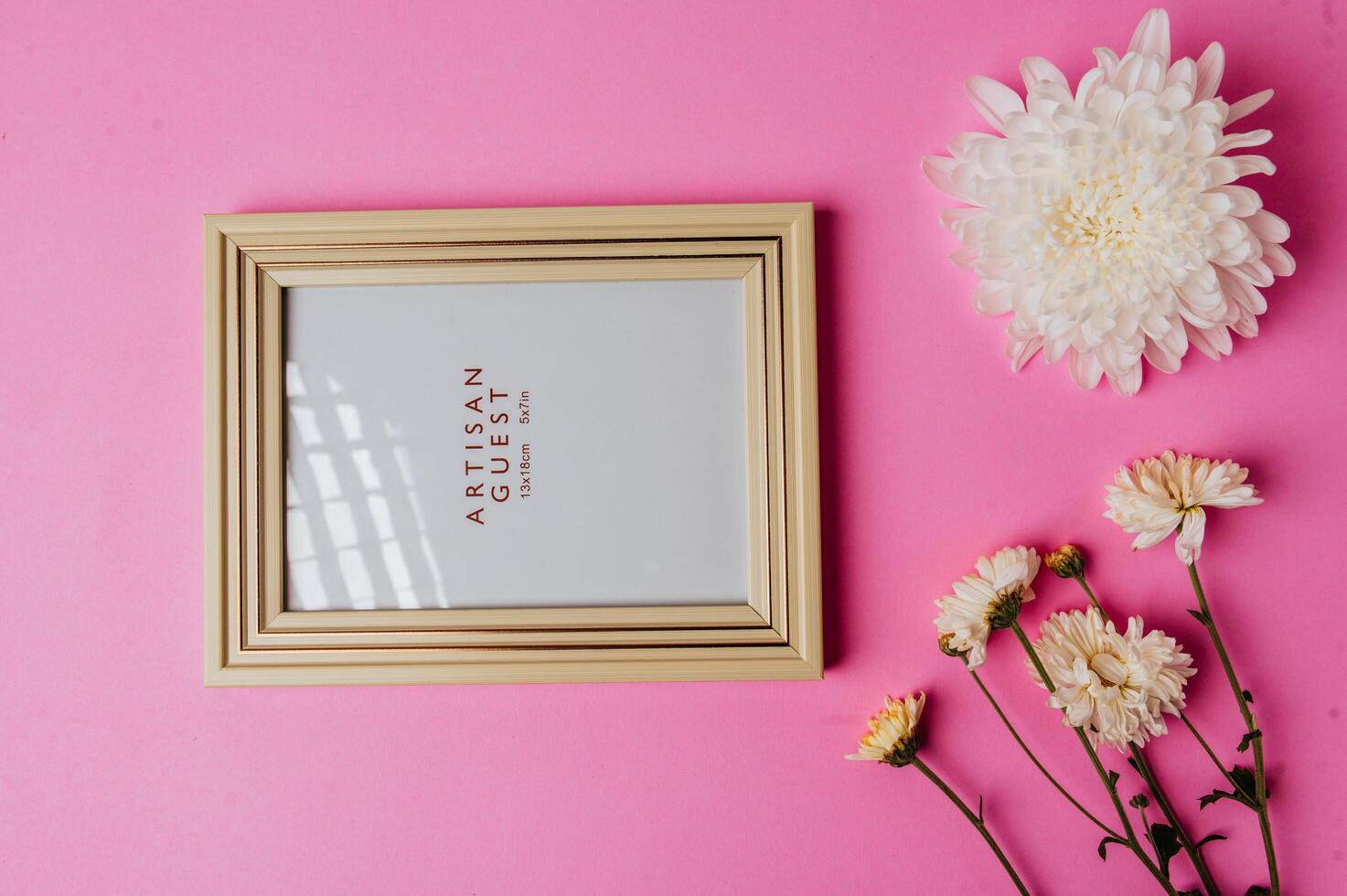 white photo frame with flower on pink background