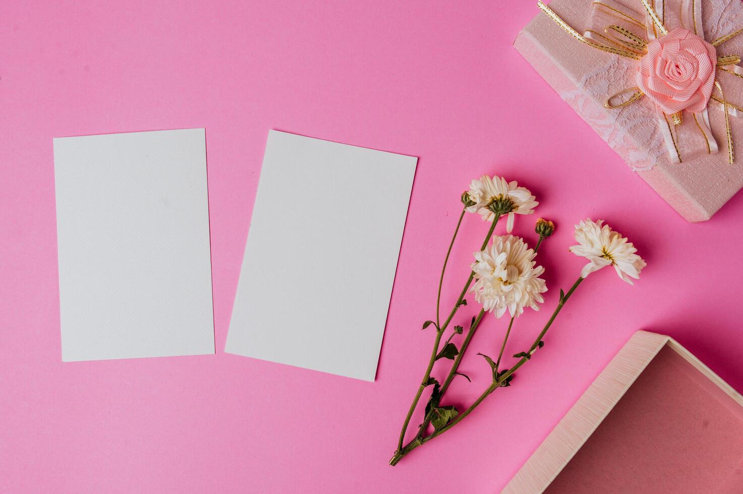 Caja de regalo rosa, flor y tarjeta en blanco sobre fondo rosa foto