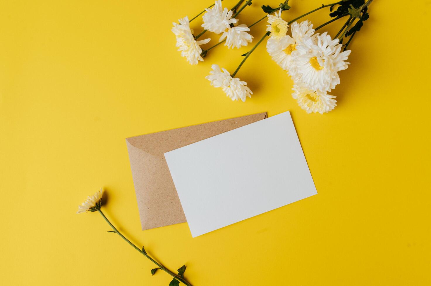 A blank card with envelope and flower is placed on yellow background photo