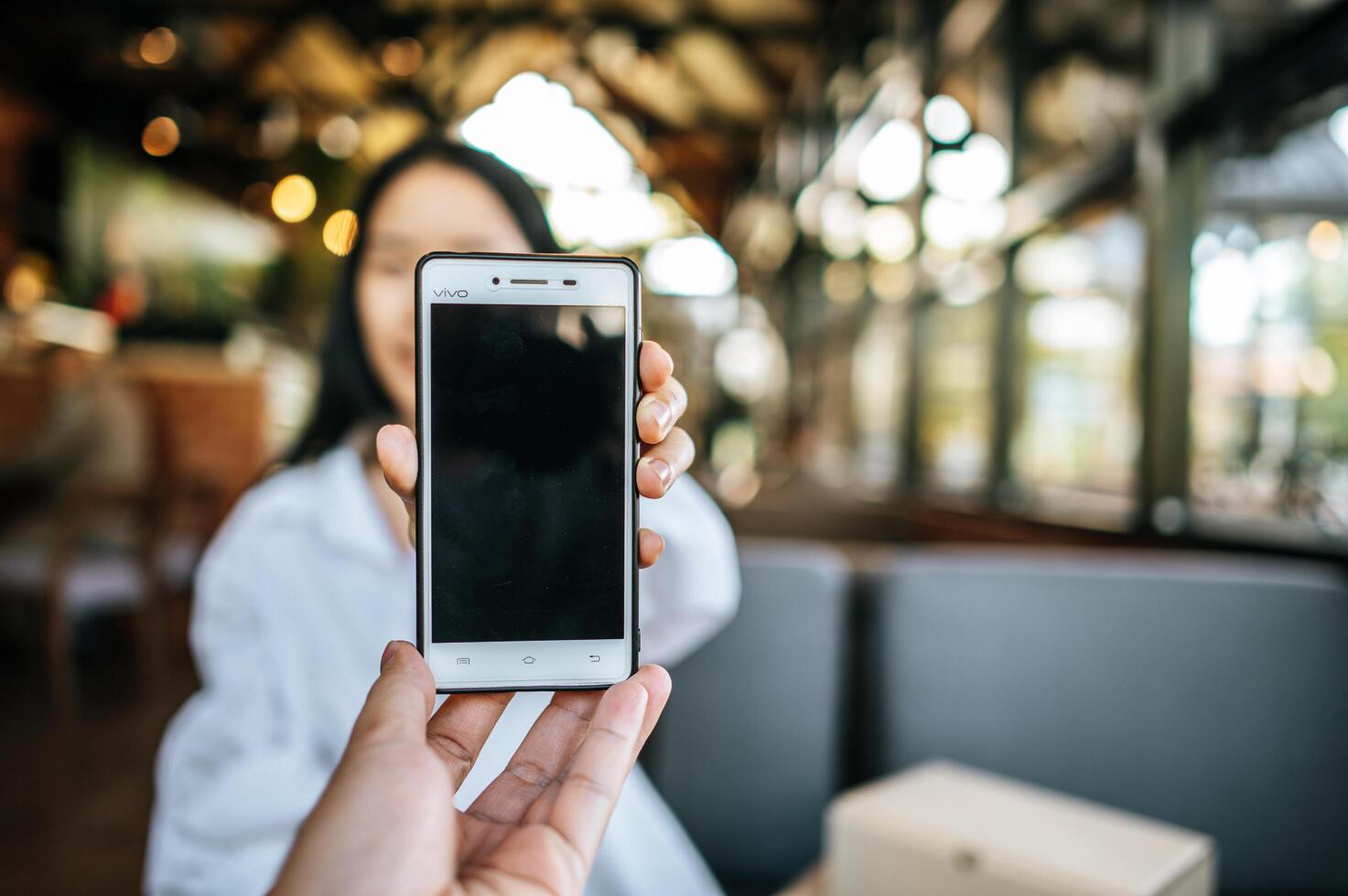 A woman holding a smartphone with her left hand and giving photo