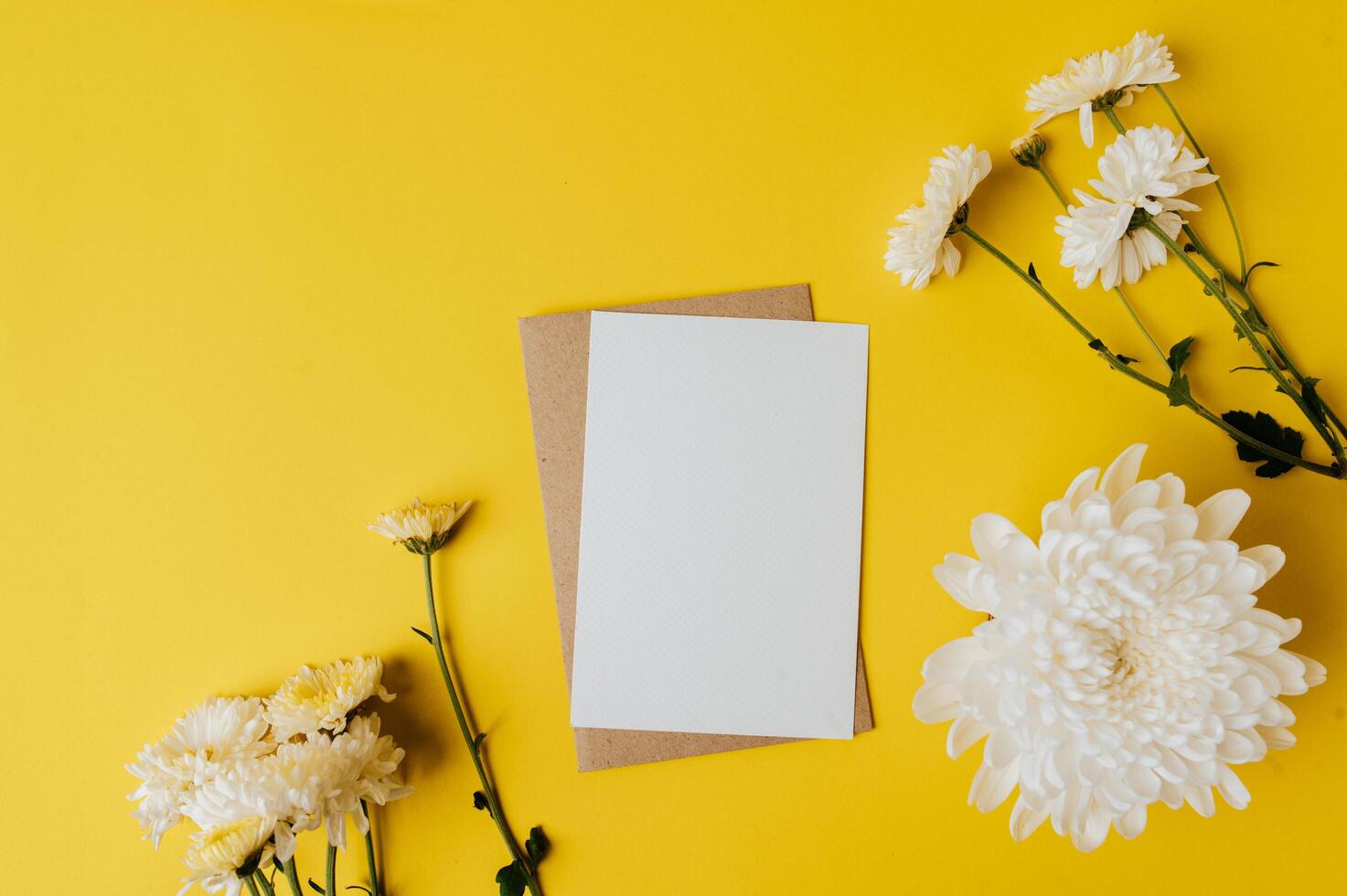 A blank card with envelope and flowers is placed on yellow background photo