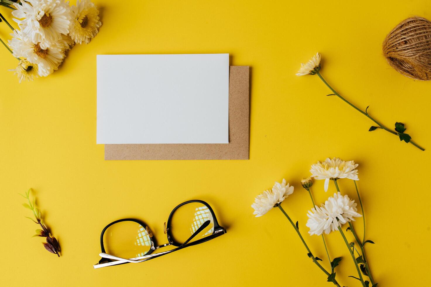 blank card with envelope, glasses and flower is placed on yellow photo