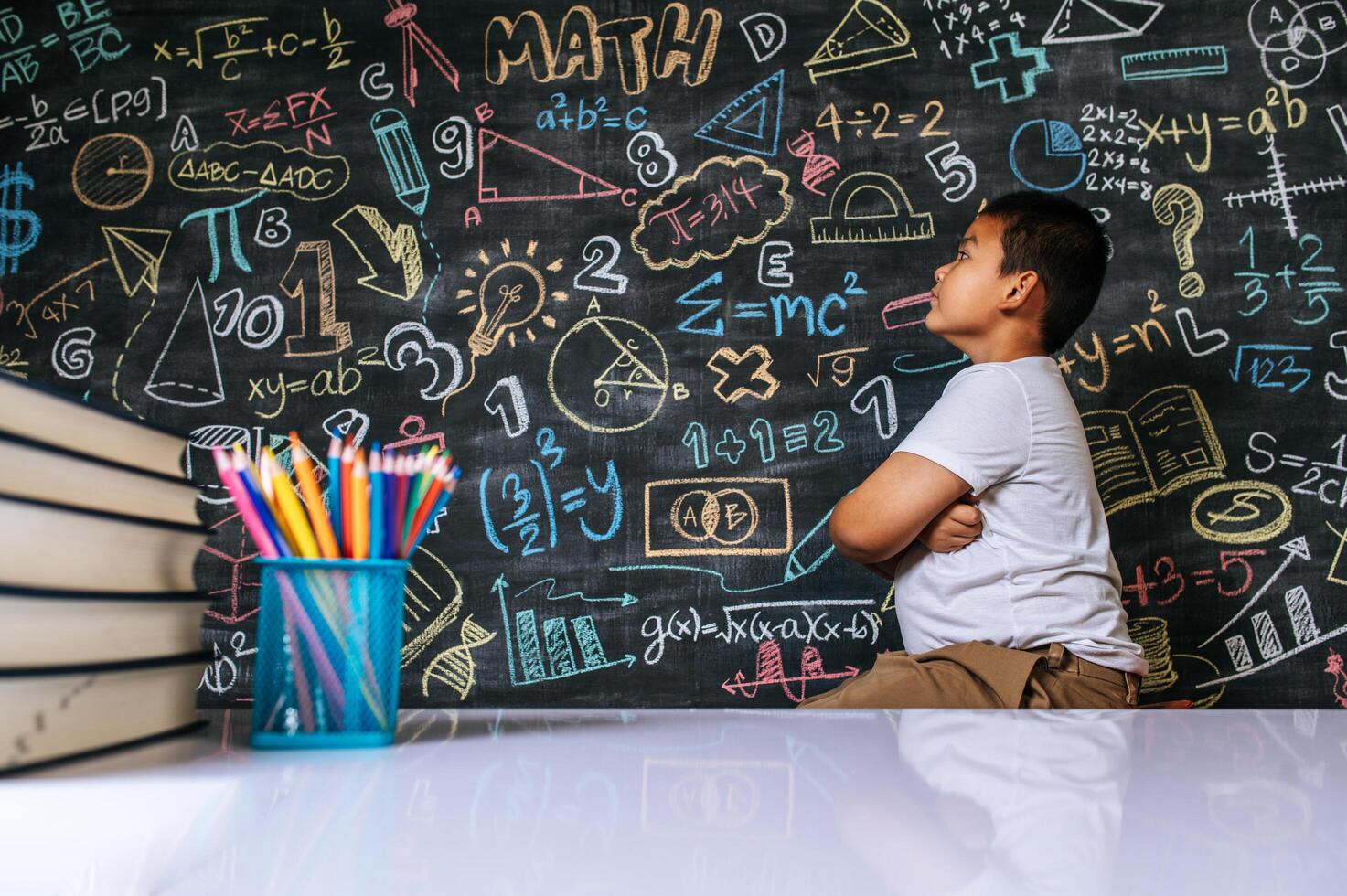 Child sitting with arms folded in the classroom photo