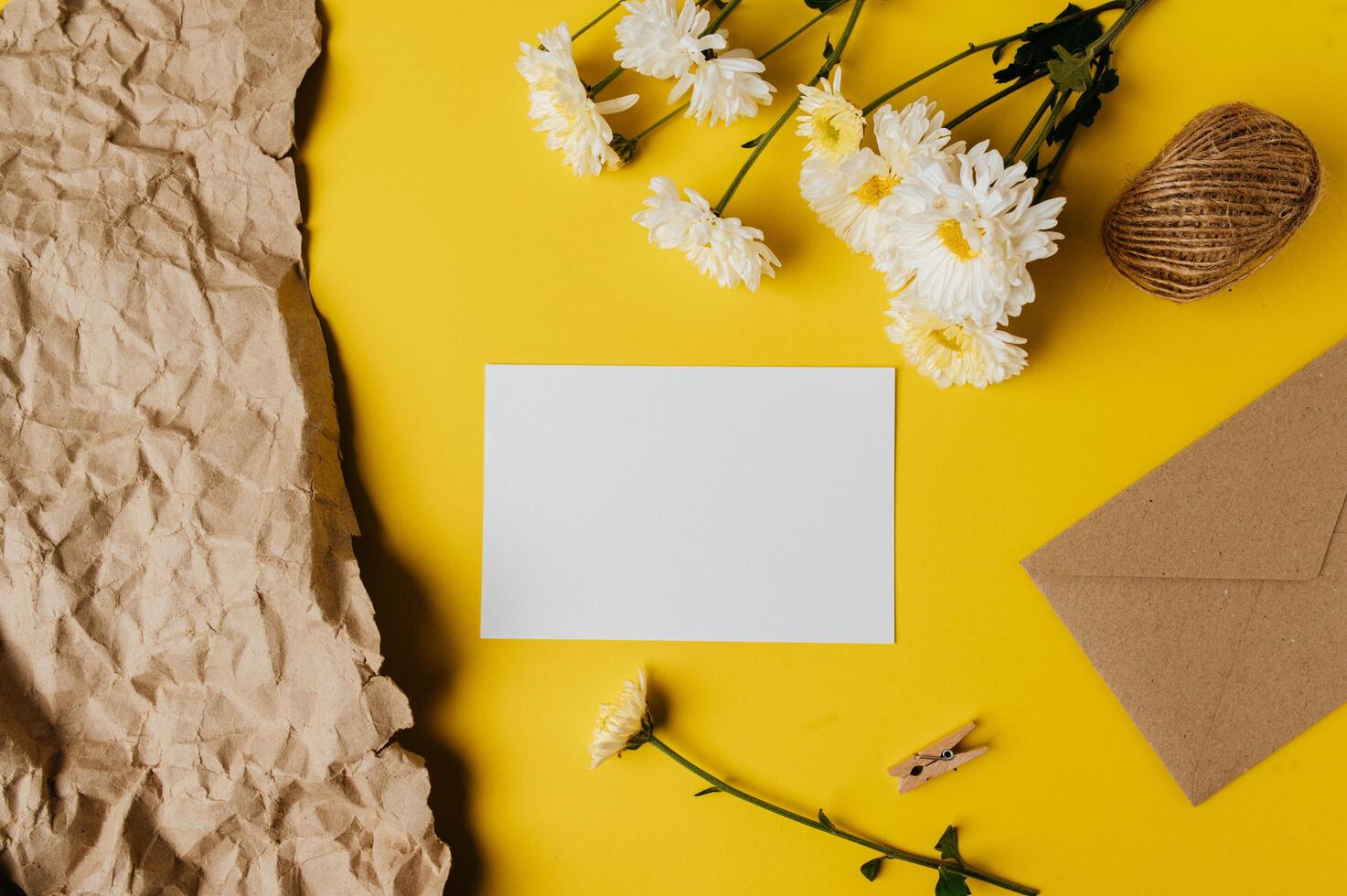 A blank card with envelope and flower is placed on yellow background photo