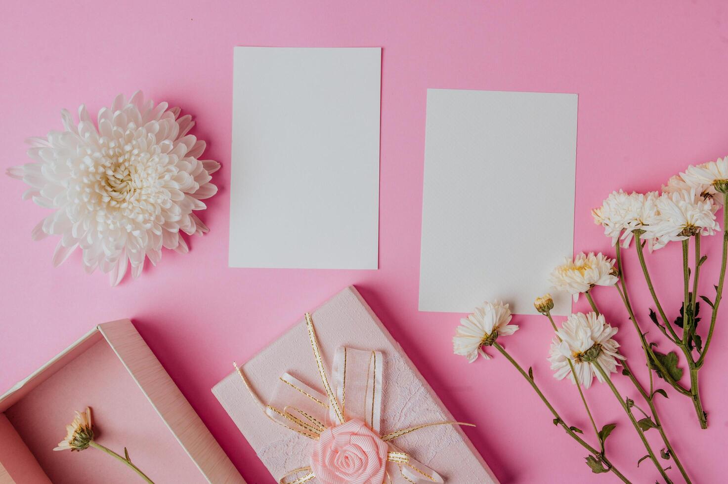 Caja de regalo rosa, flor y tarjeta en blanco sobre fondo rosa foto