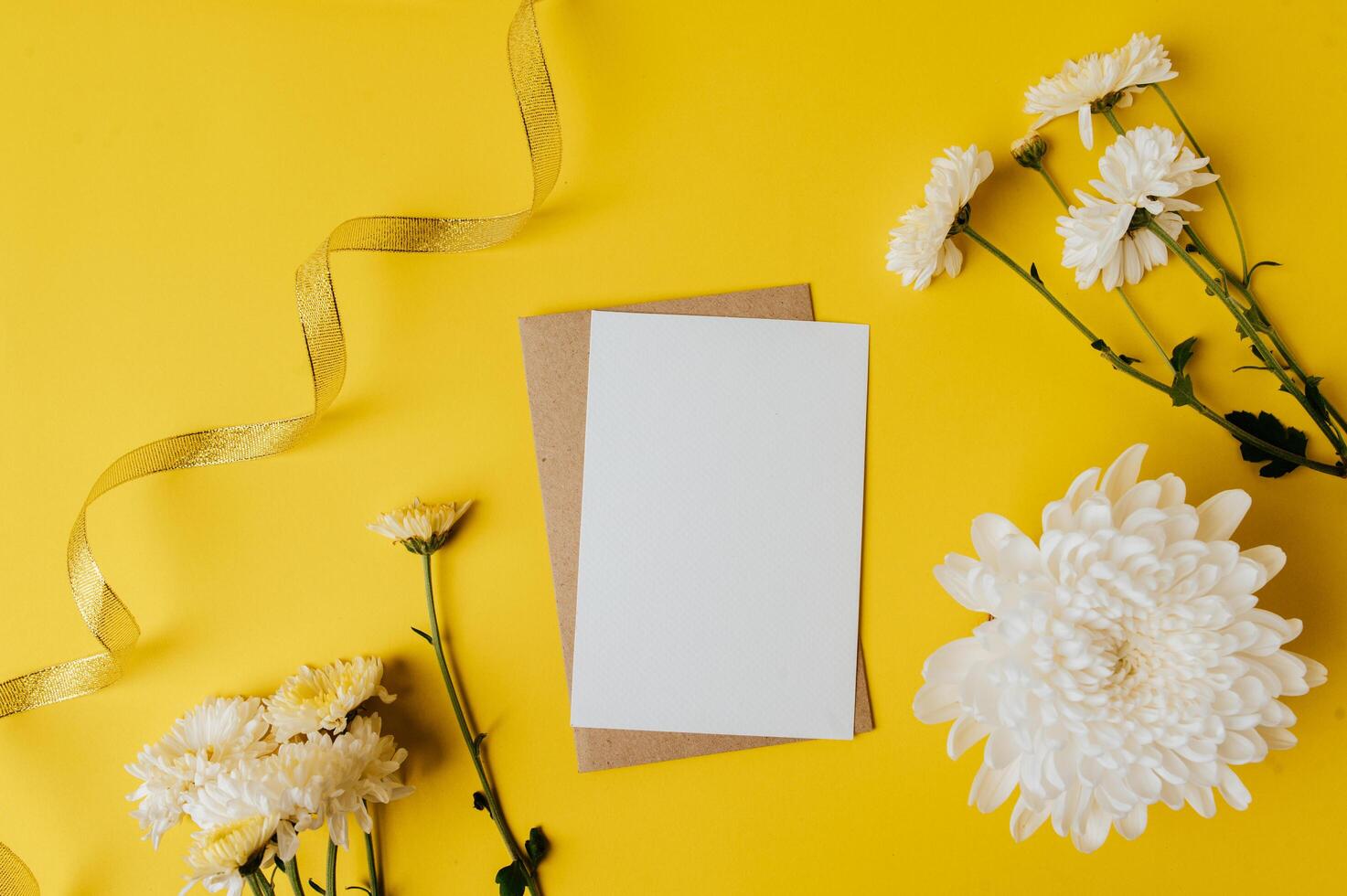 A blank card with envelope and flowers is placed on yellow background photo