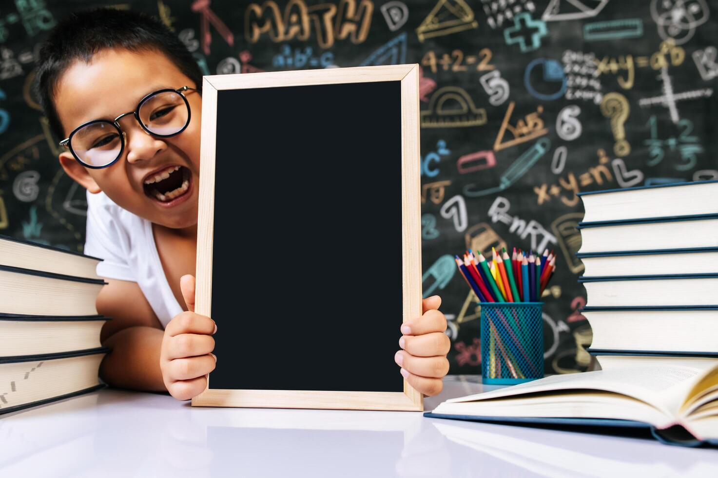 niño sentado y sosteniendo la pizarra en el aula foto