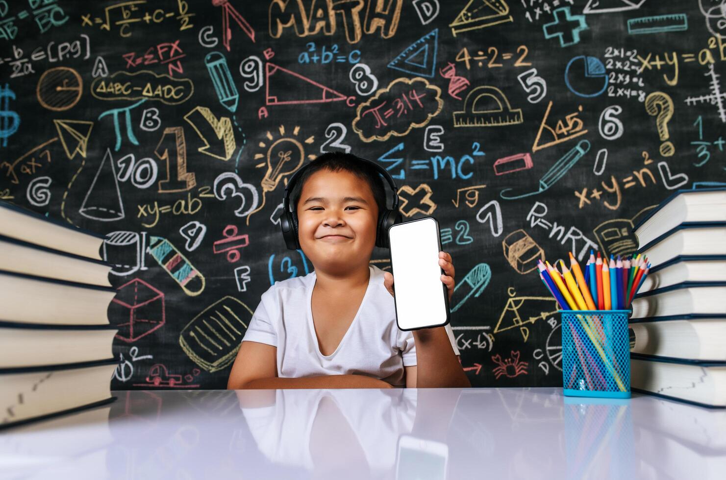 Child sitting and showing mobile in the classroom photo