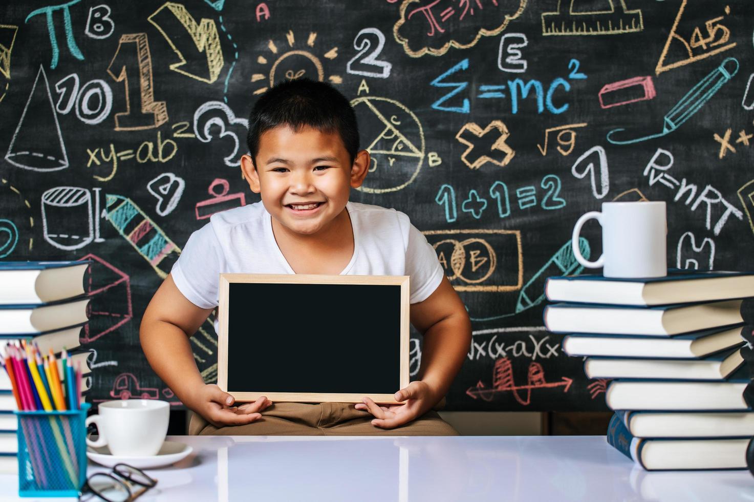 Child sitting and holding blackboard in the classroom photo